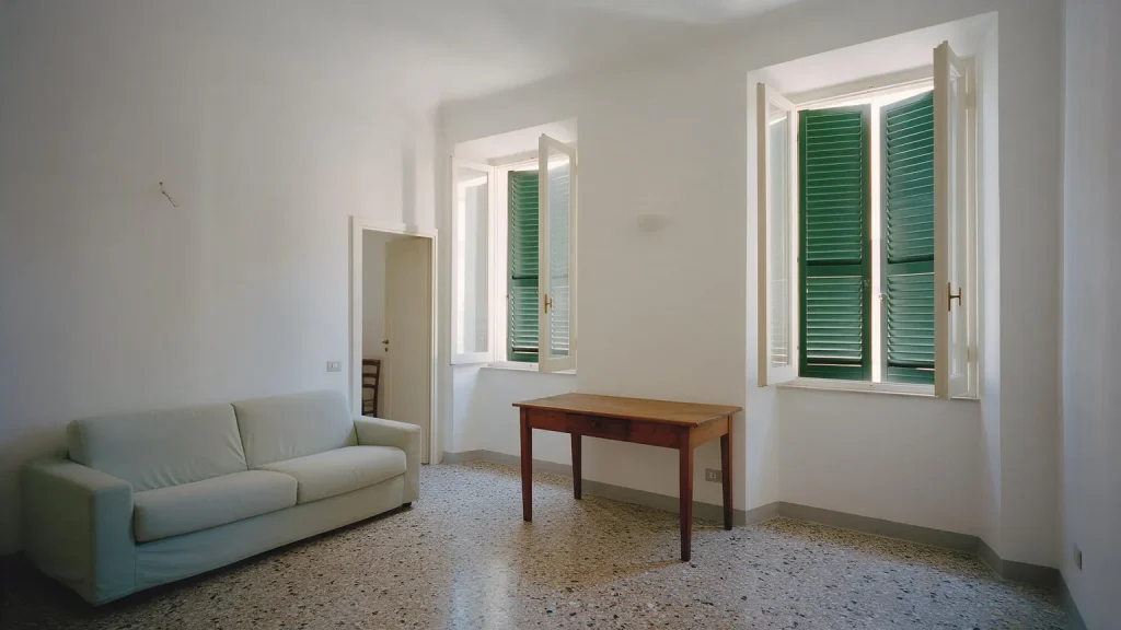 Salotto di una casa ristrutturata con divano chiaro e finestre aperte